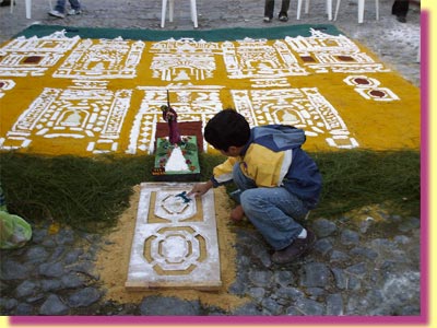 A liitle boy finishing a carpet that shows a procession, with Jesus, leaving the front of the La Merced church, only a couple of blocks from the actual church
